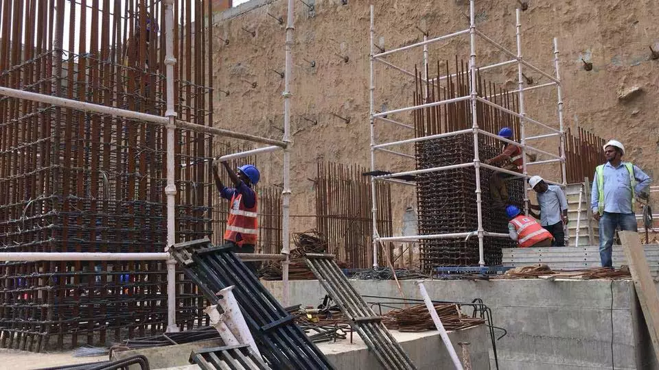 Construction worker wearing a blue hat, fixing a metal wall cage