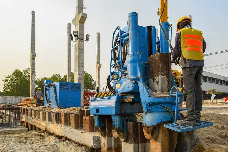 A worker working a hammer-driven sheet piling construction Caption: Sheet piling comes with many benefits for deep basement construction